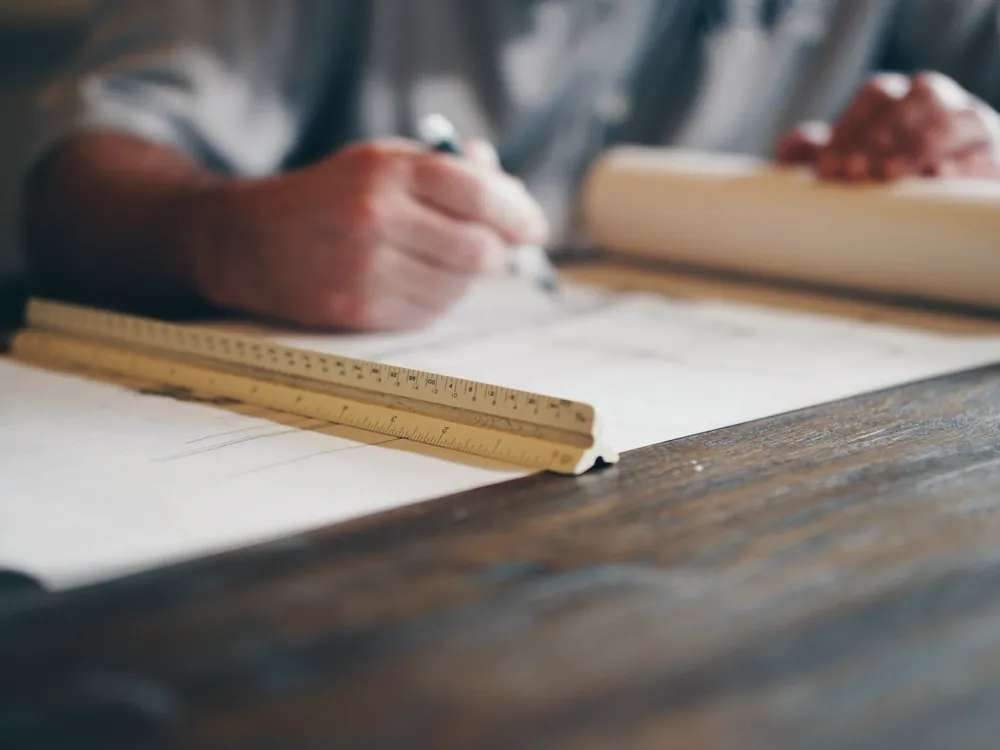 Mains traçant un plan à la règle sur une table de bois