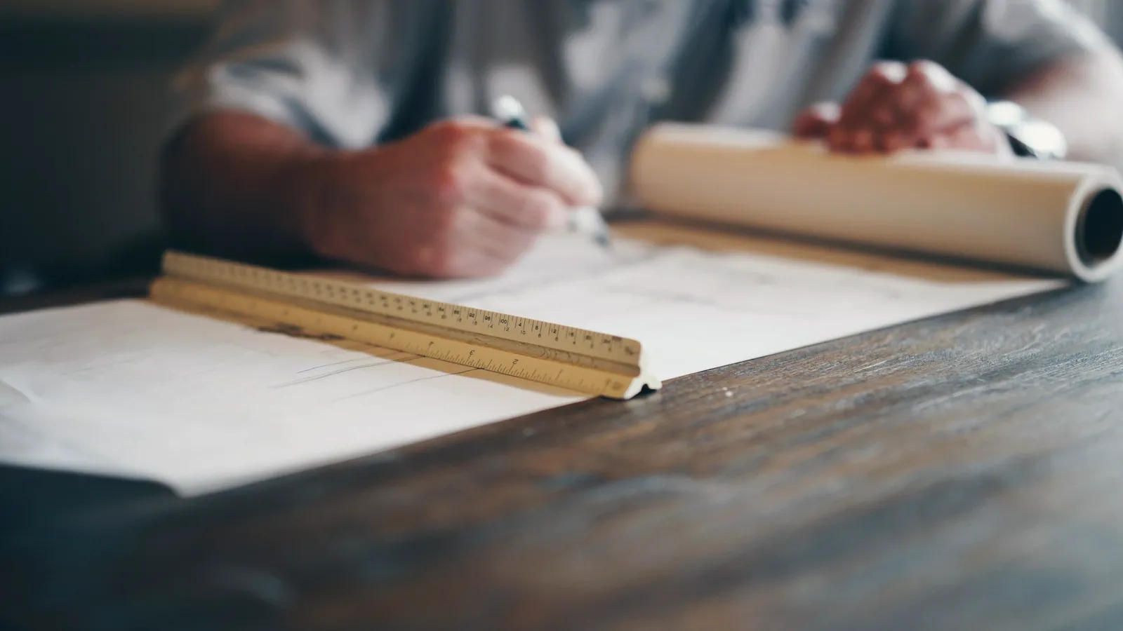 Mains traçant un plan à la règle sur une table de bois