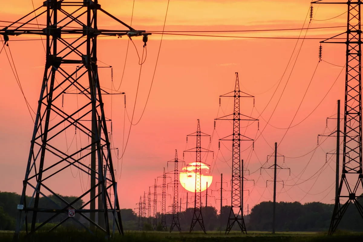 Pylônes et lignes à haute tension découpés sur un ciel de coucher de soleil
