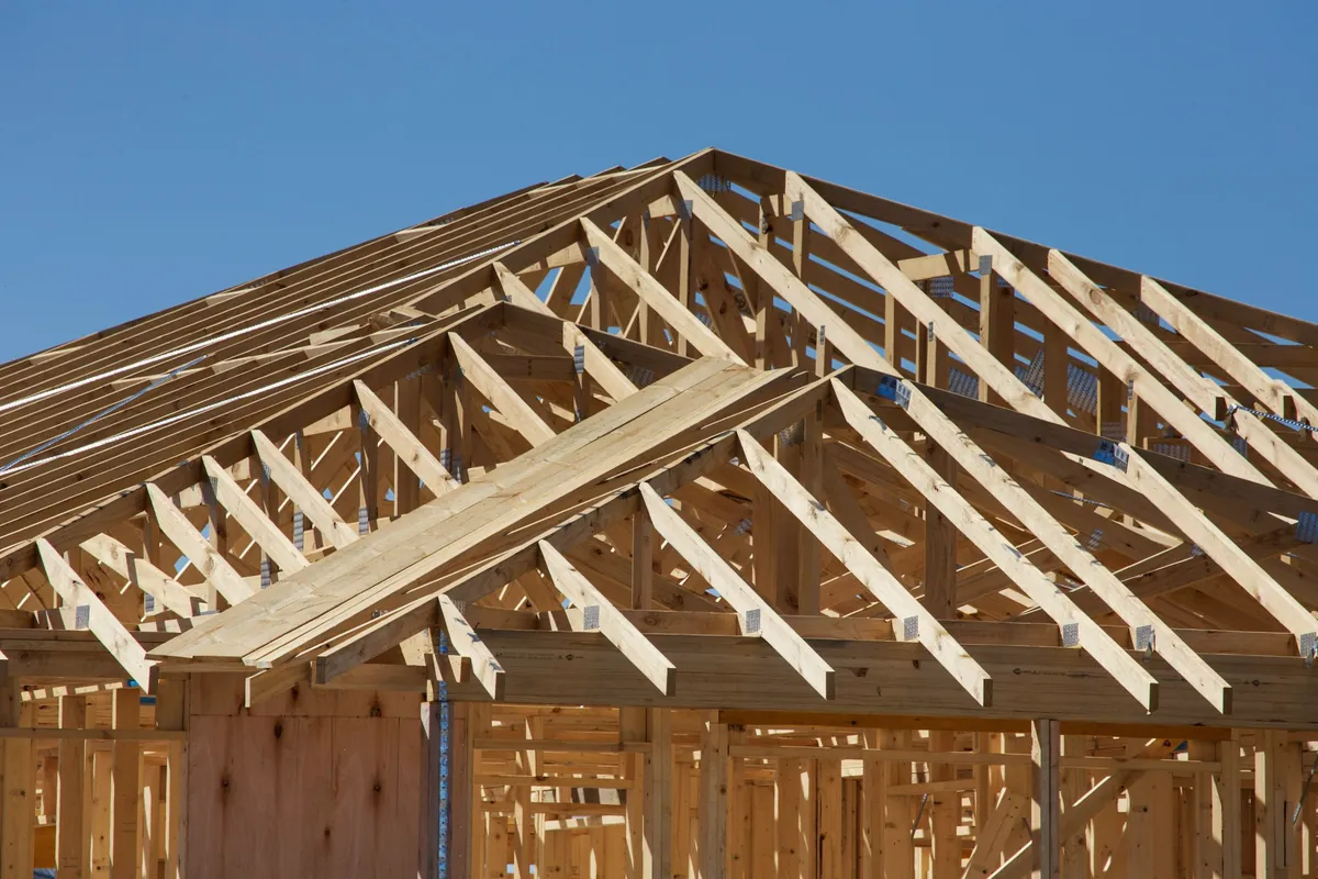 Charpente en bois d’une maison en construction sous un ciel bleu